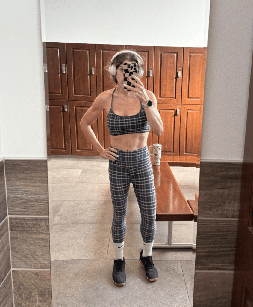 fit girl in plaid workout set posing in the mirror at the gym. 